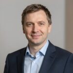 Портрет уверенного российского предпринимателя с дружелюбным взглядом на нейтральном размытом фоне в студии