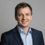 Портрет уверенного российского предпринимателя с дружелюбным взглядом на нейтральном размытом фоне в студии